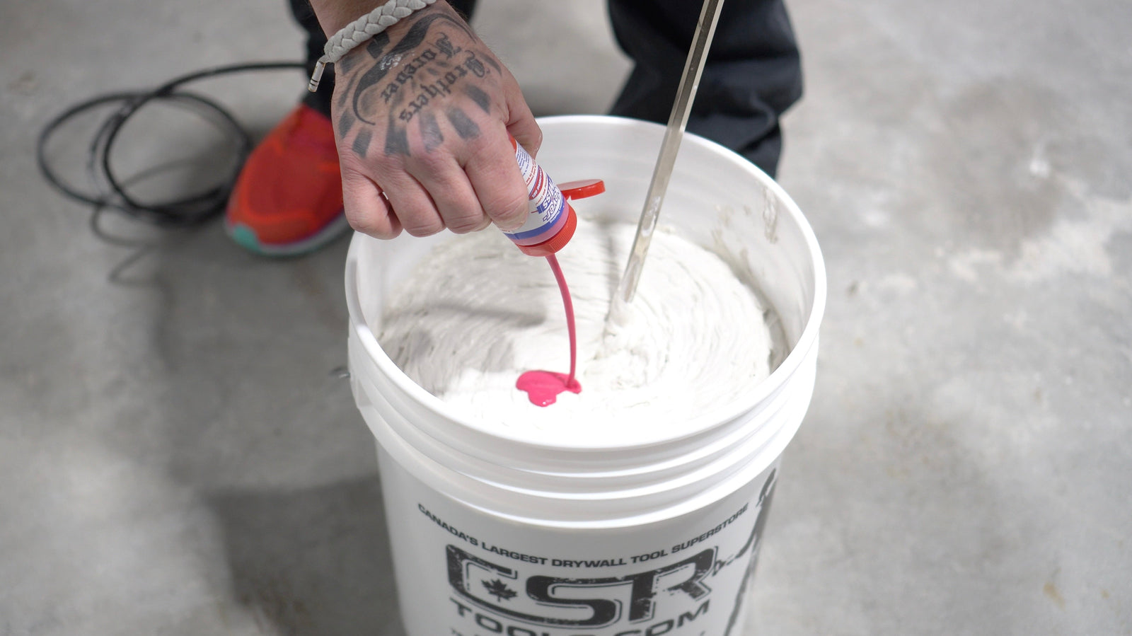 Drywall finisher pouring Pink Never-Miss Colouring Gel into a bucket